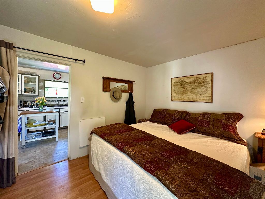 Bedroom with a large bed and patterned brown bedding, opening into the kitchen.