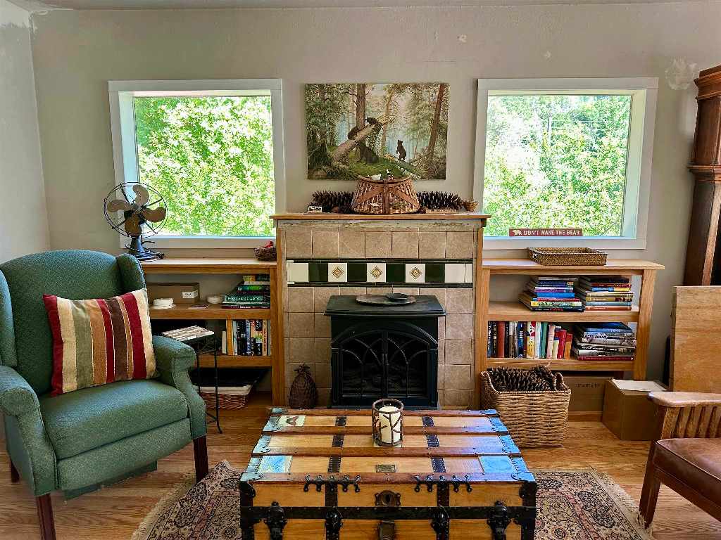 Living room with tiled fireplace, built-in bookshelves, green armchair, and wooden trunk coffee table.