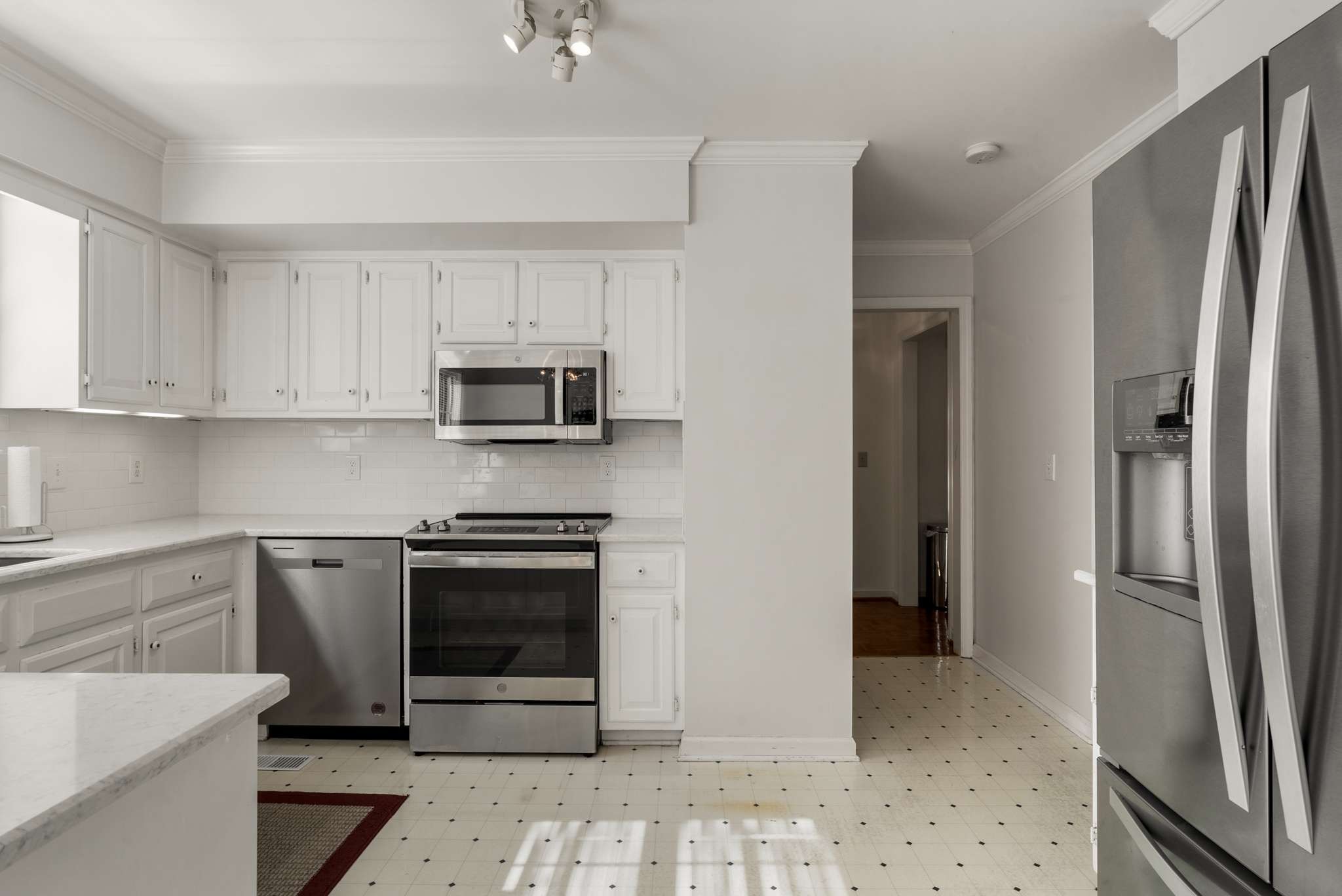Kitchen with white cabinets and tile, stainless steel appliances, and a large refrigerator.