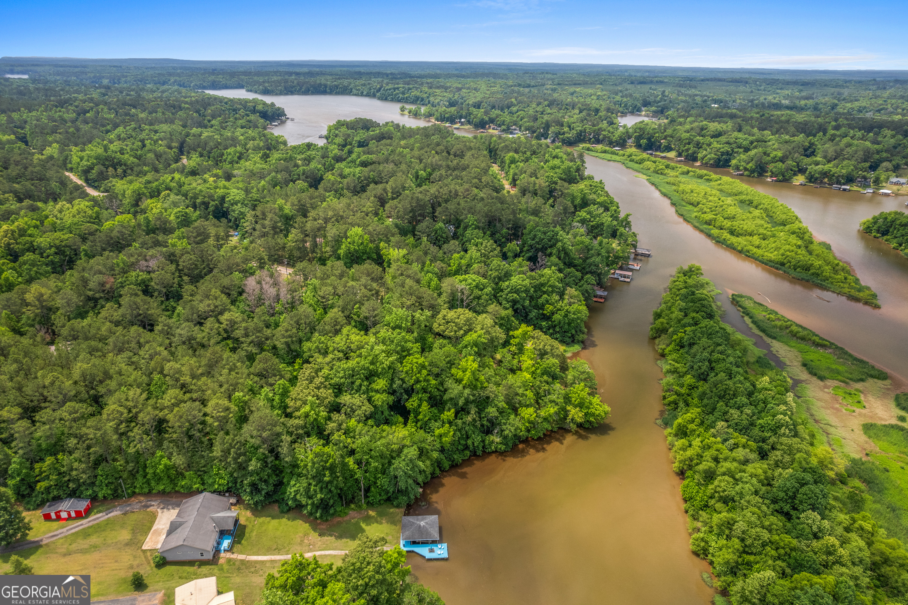 Aerial view of a wooded cove with shoreline homes and docks.