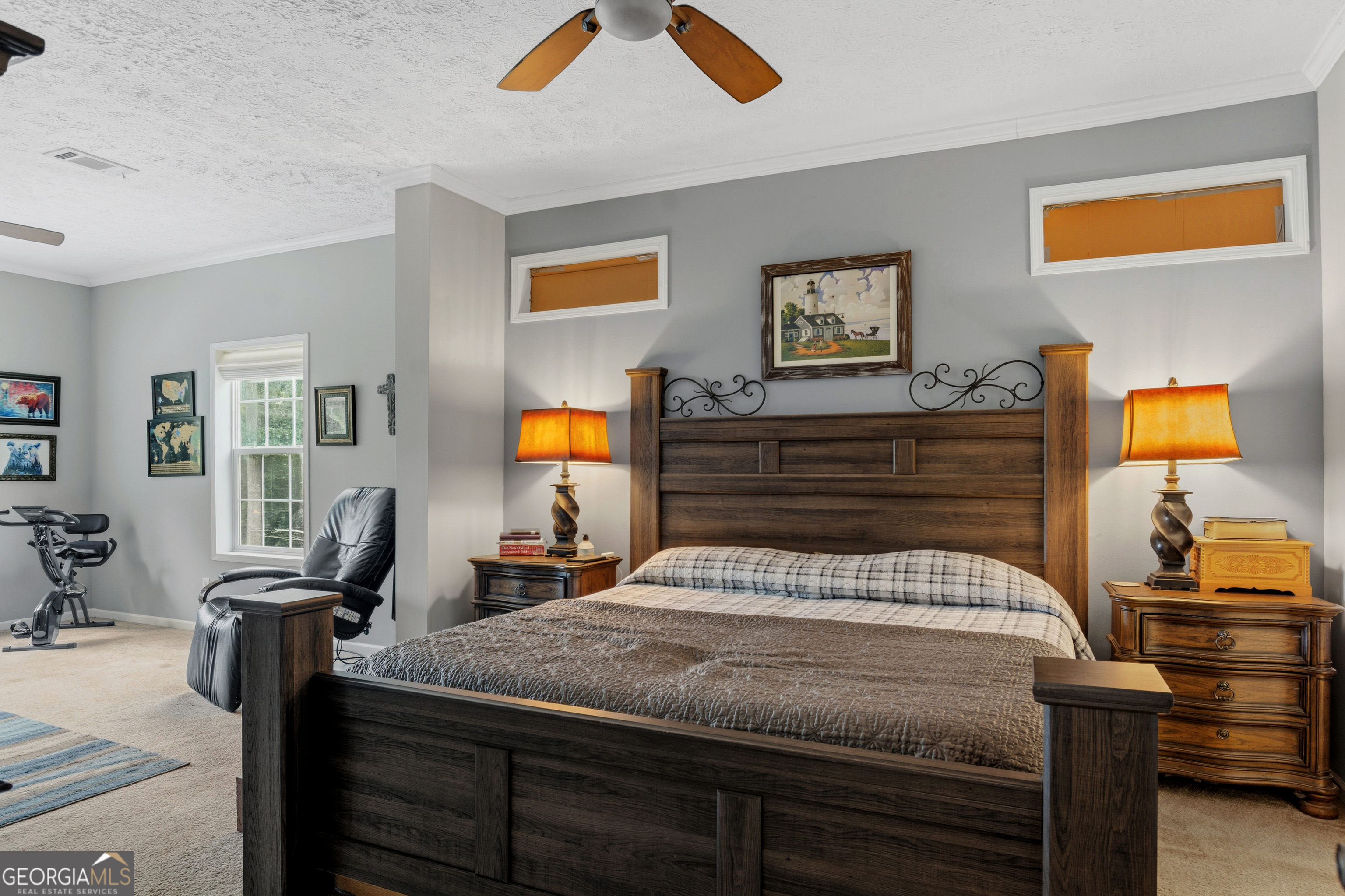Furnished bedroom with a large dark wood bed, matching bedside tables, orange lamps, and a leather chair.