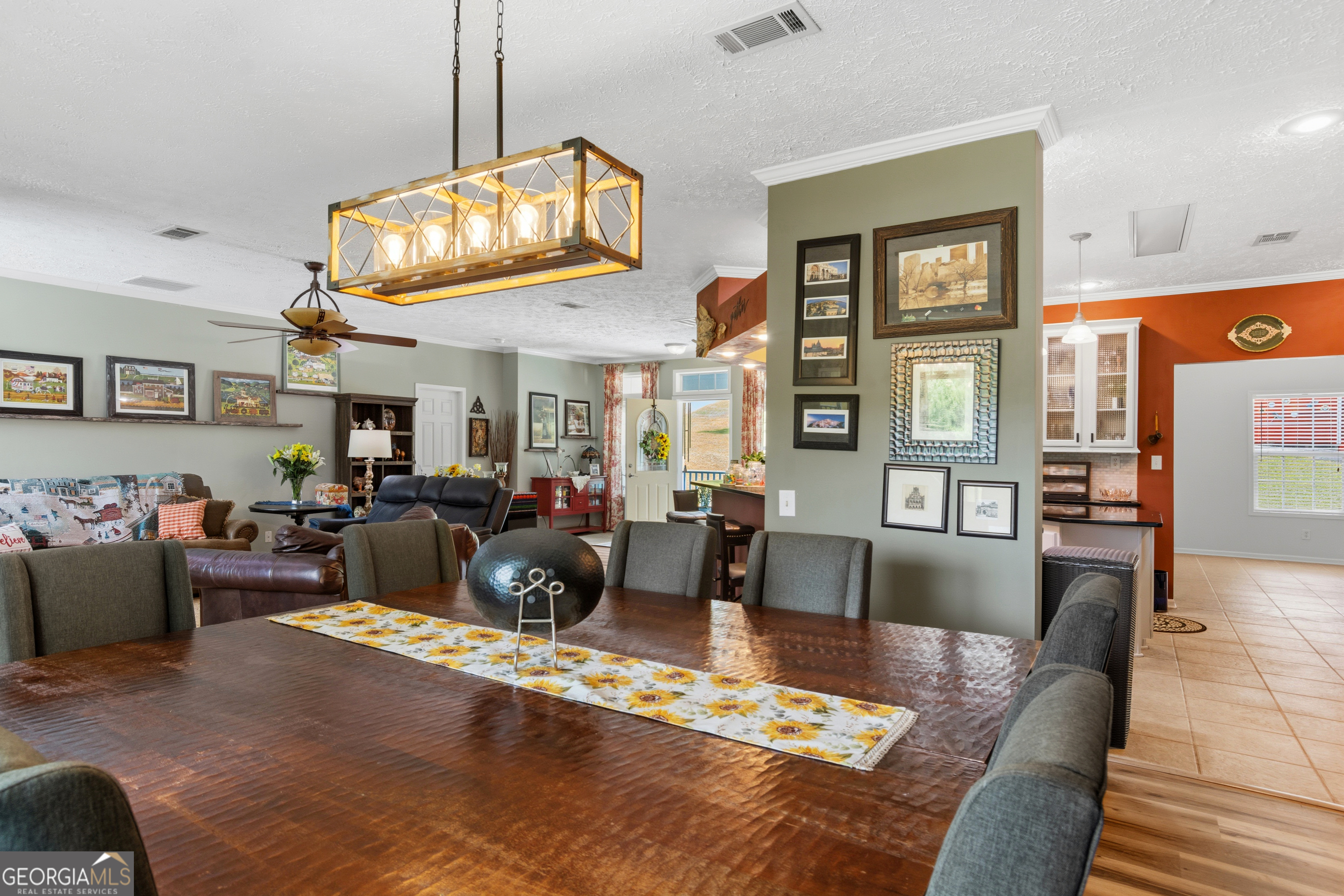 Dining room with a large wood table and chandelier, open to a living room and kitchen.