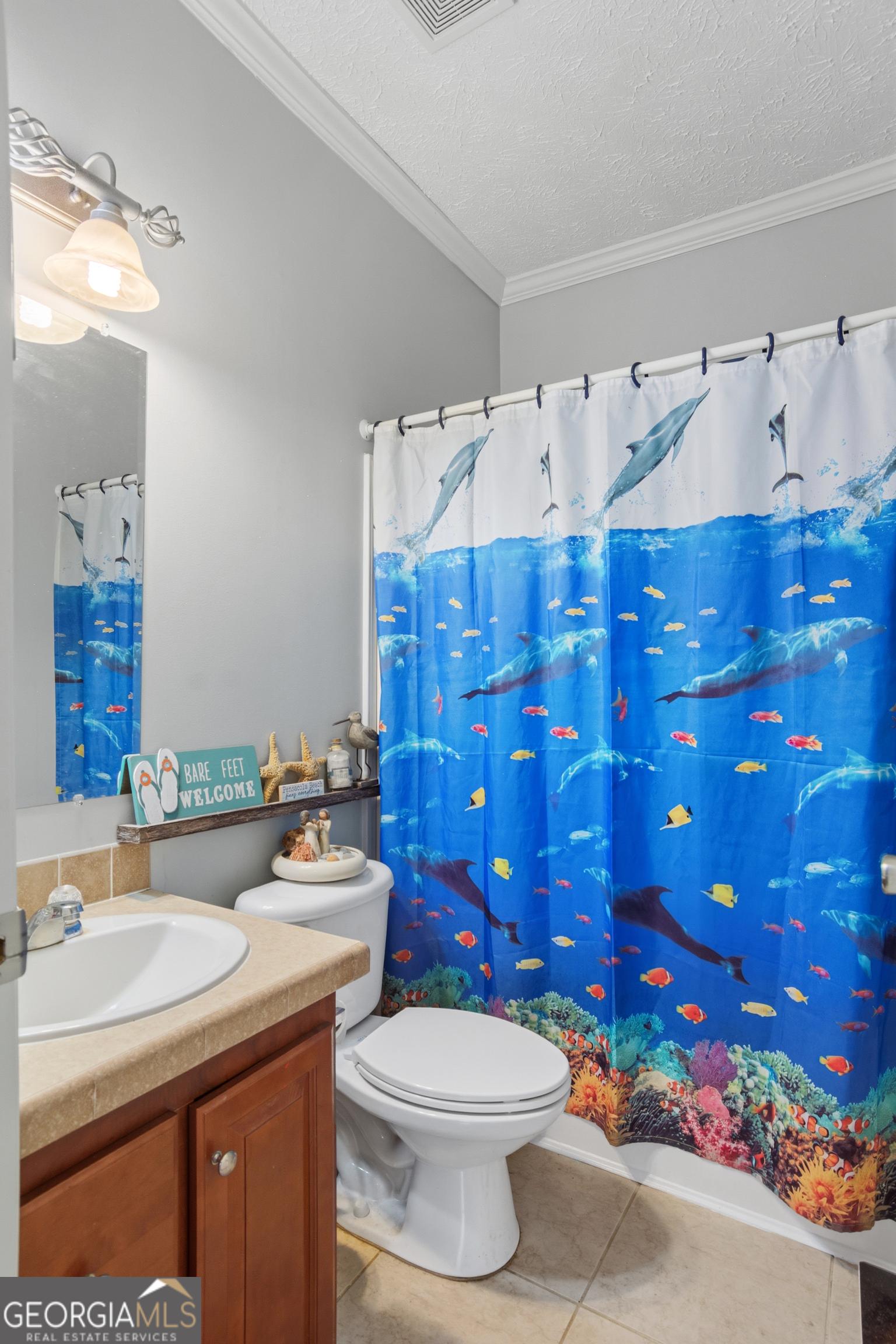 Bathroom with a vivid blue dolphin-and-fish shower curtain and dark wood vanity.