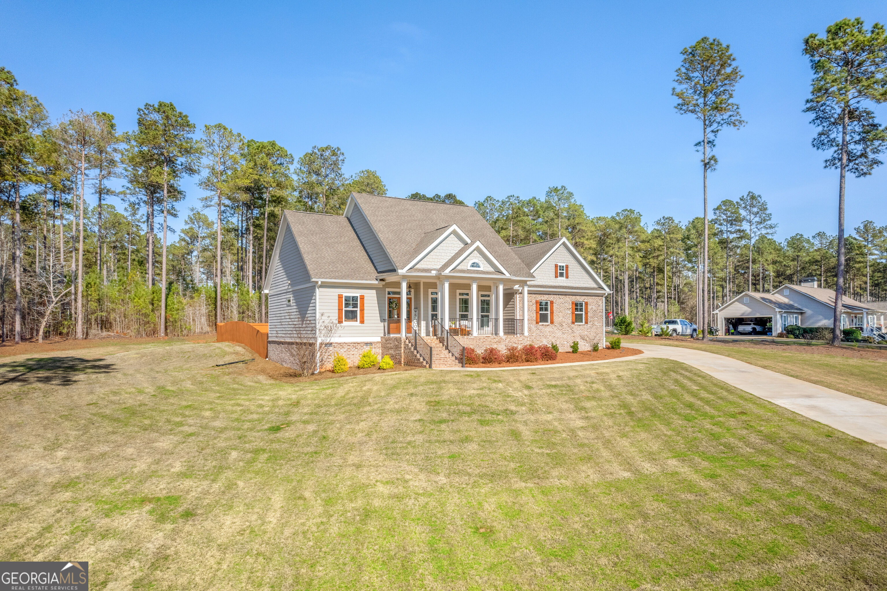 Home with brick-and-siding exterior, columned front porch, broad lawn, and curved driveway.
