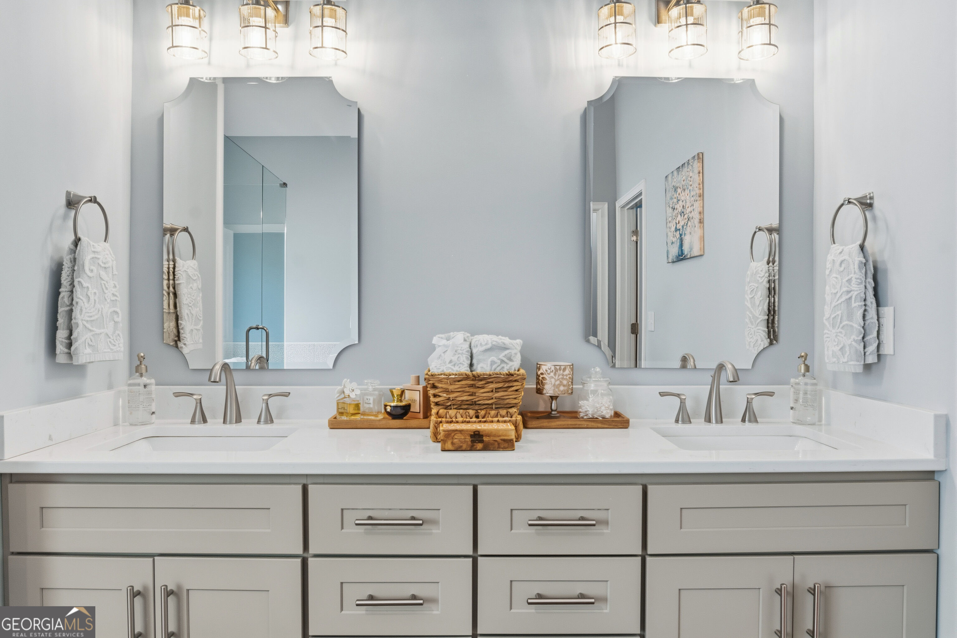 Bathroom double vanity with two sinks, framed mirrors, and white paneled cabinetry.