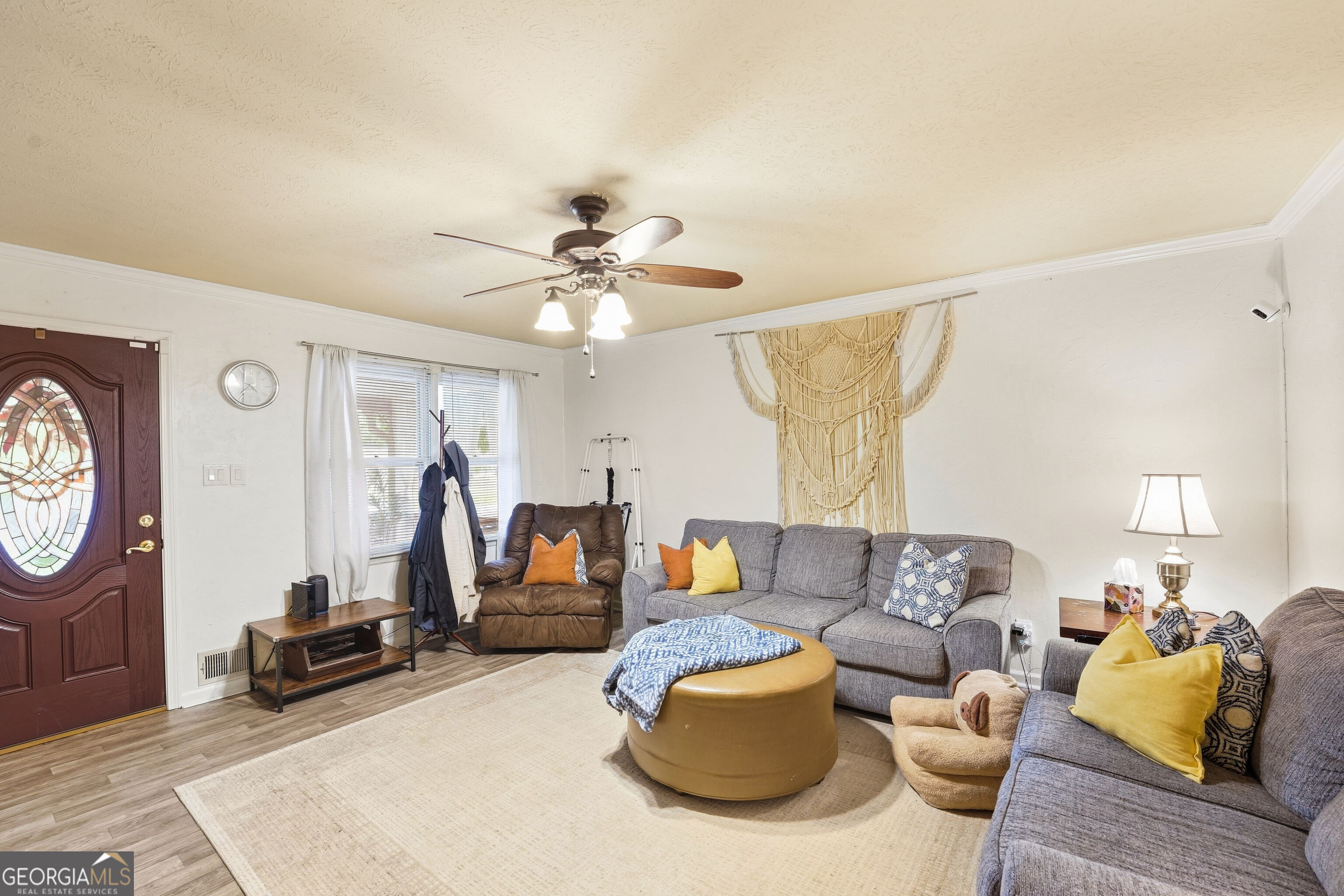 Living room with gray sofas, a brown recliner, and a round ottoman beneath a ceiling fan.