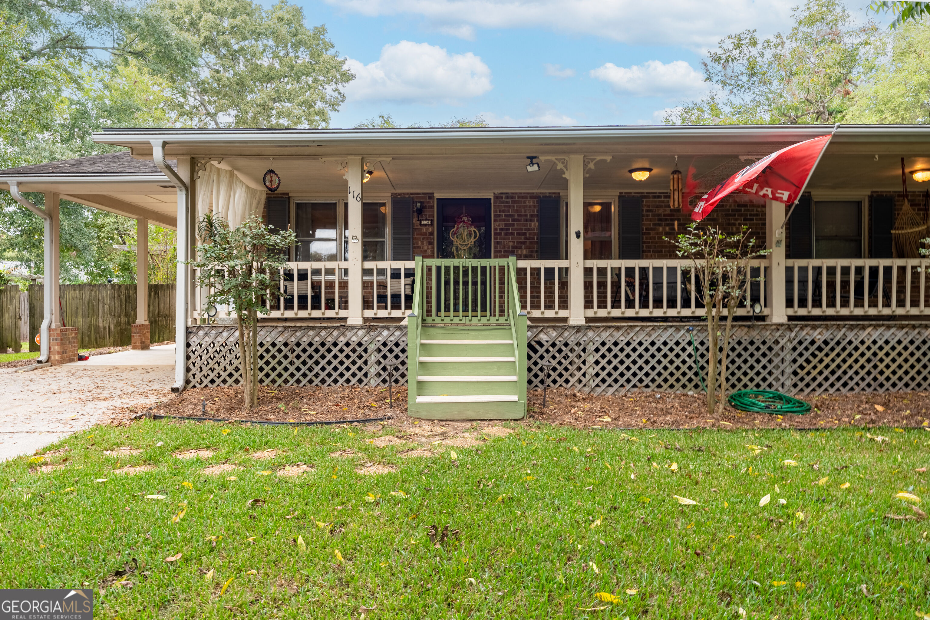 Brick home with a long covered porch, green steps, and lattice skirting across the front.