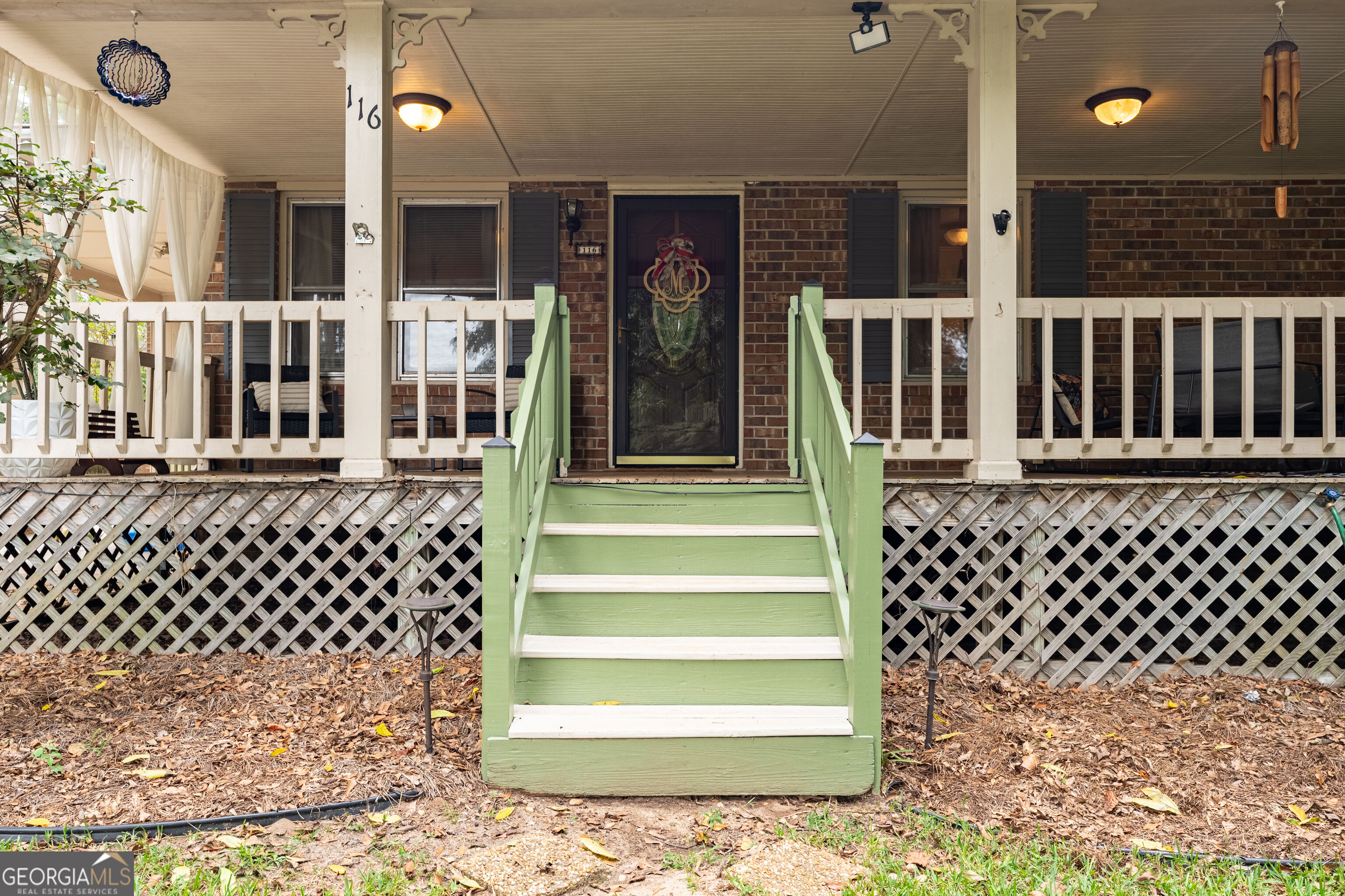 Brick home with a covered porch and pale green steps leading to a decorative glass front door.