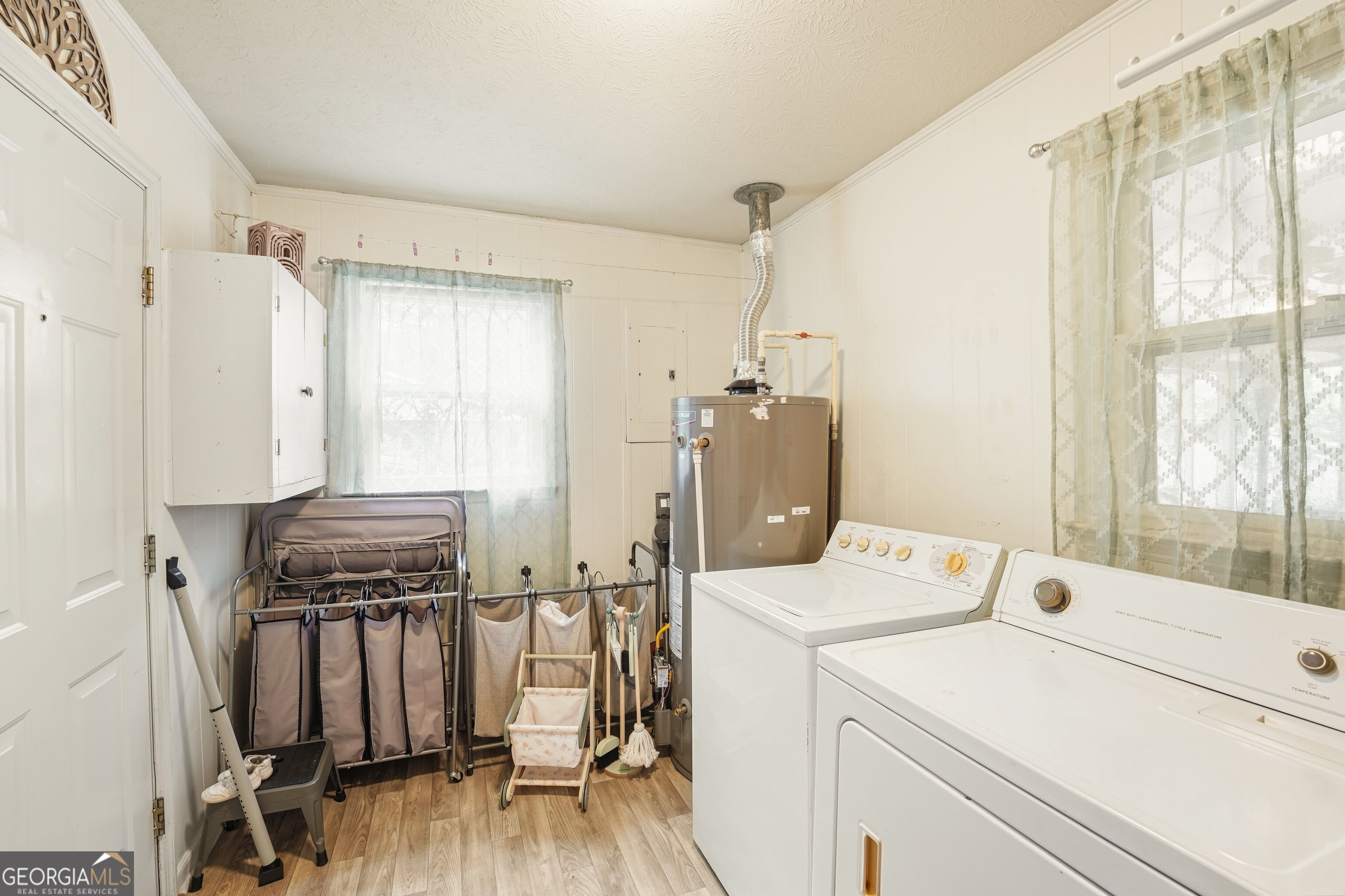 Laundry room with washer, dryer, exposed water heater, and folding laundry racks.