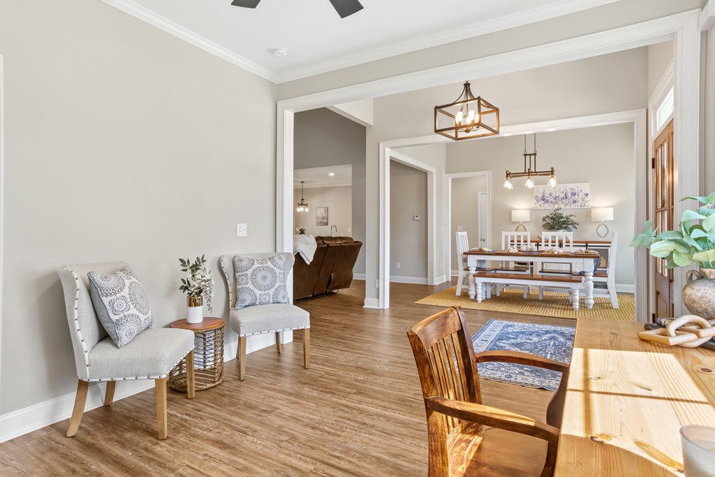 Dining area with a wooden table, white dining set, gray walls, and wood flooring.