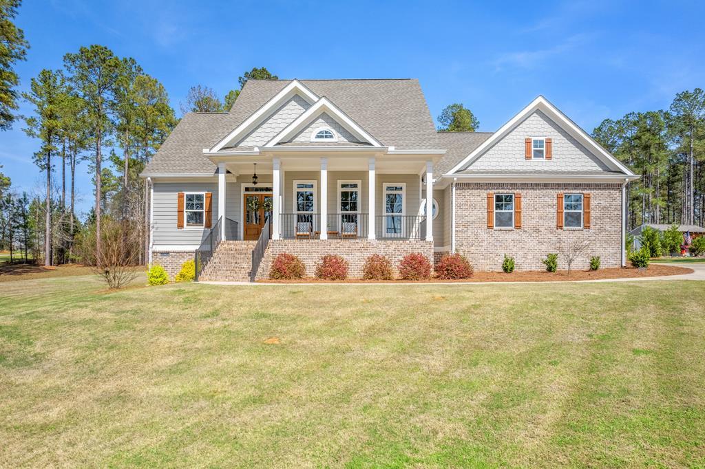 Large brick-and-siding home with a columned front porch and broad lawn.