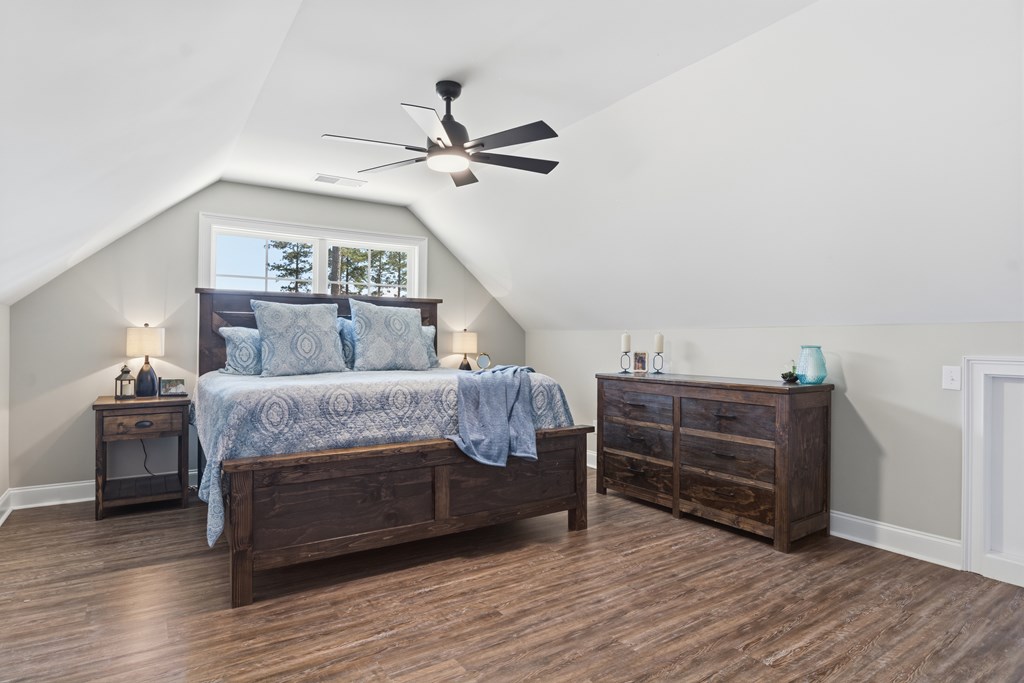 Bedroom with a bed beneath a window, sloped ceilings, and dark wood furniture.