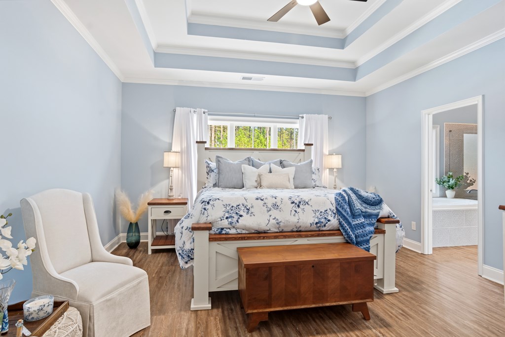 Bedroom with a tray ceiling, floral bedding, and a doorway to an adjoining bathroom.