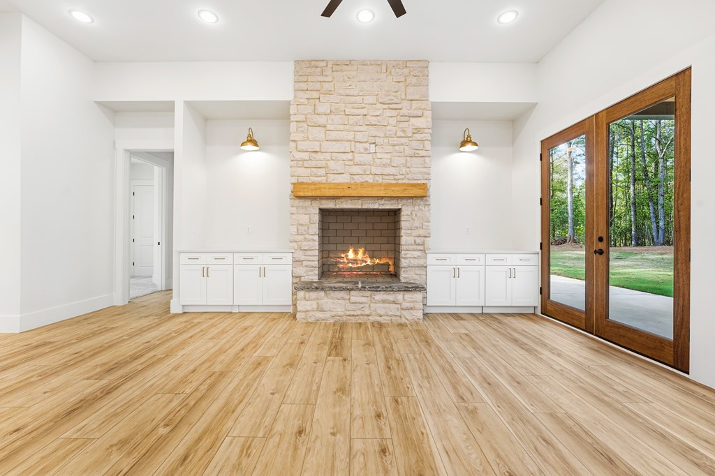 Unfurnished living room with a stone fireplace and wood-framed patio doors.