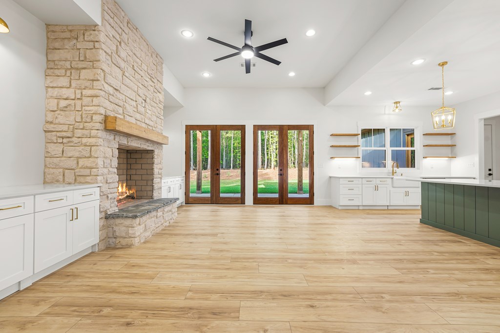 Open kitchen with a stone fireplace, green island, and wood-framed doors to the wooded backyard.