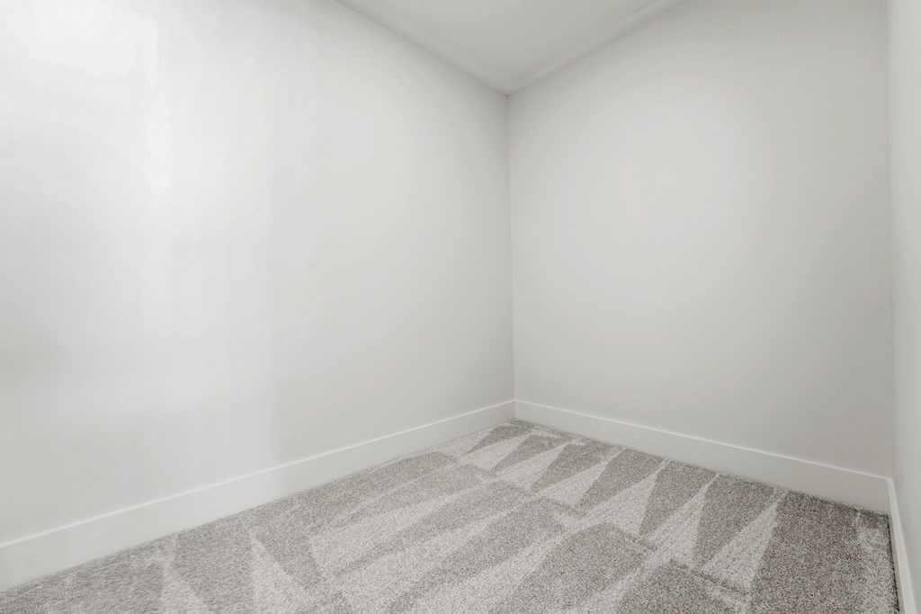 Empty room with white walls and light gray patterned carpet.