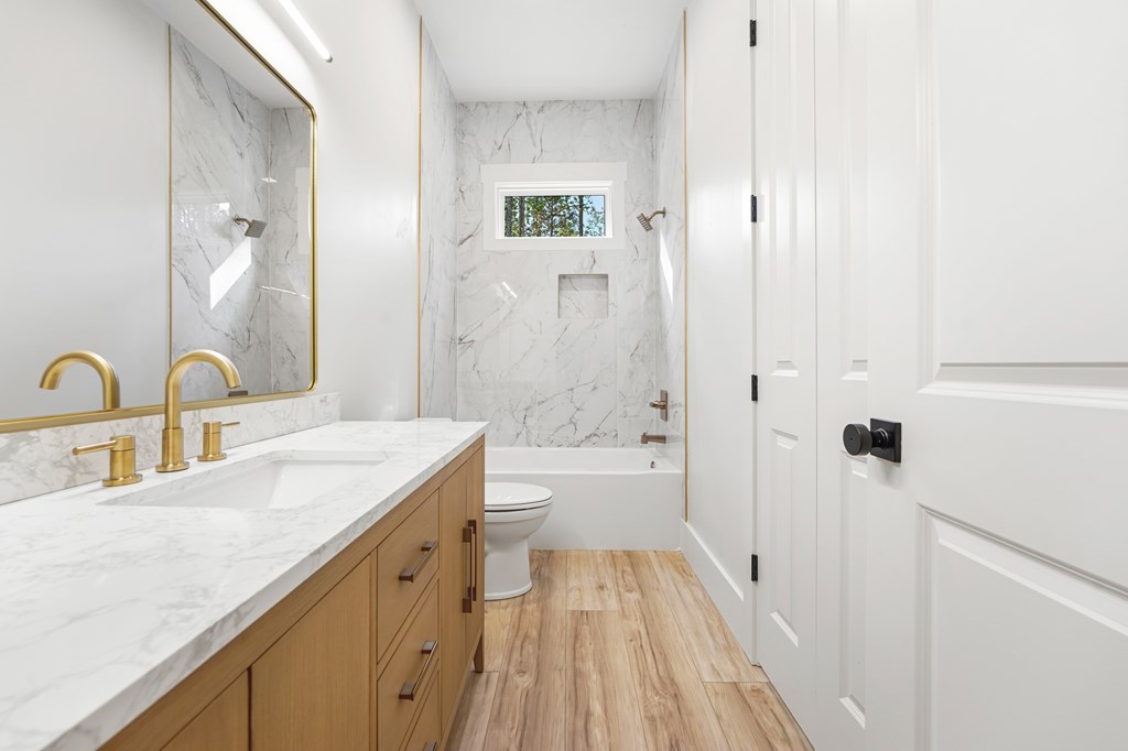 Bathroom with a marble double vanity, brass faucets, and a tub and shower.