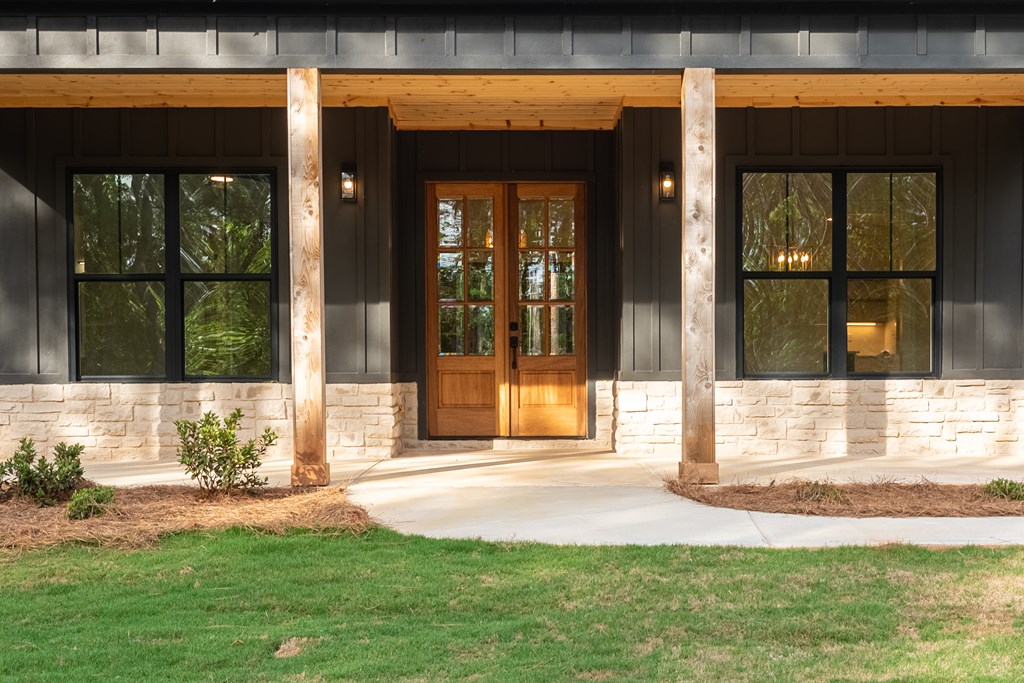 House entrance with double wooden doors, timber porch posts, and a light stone facade.