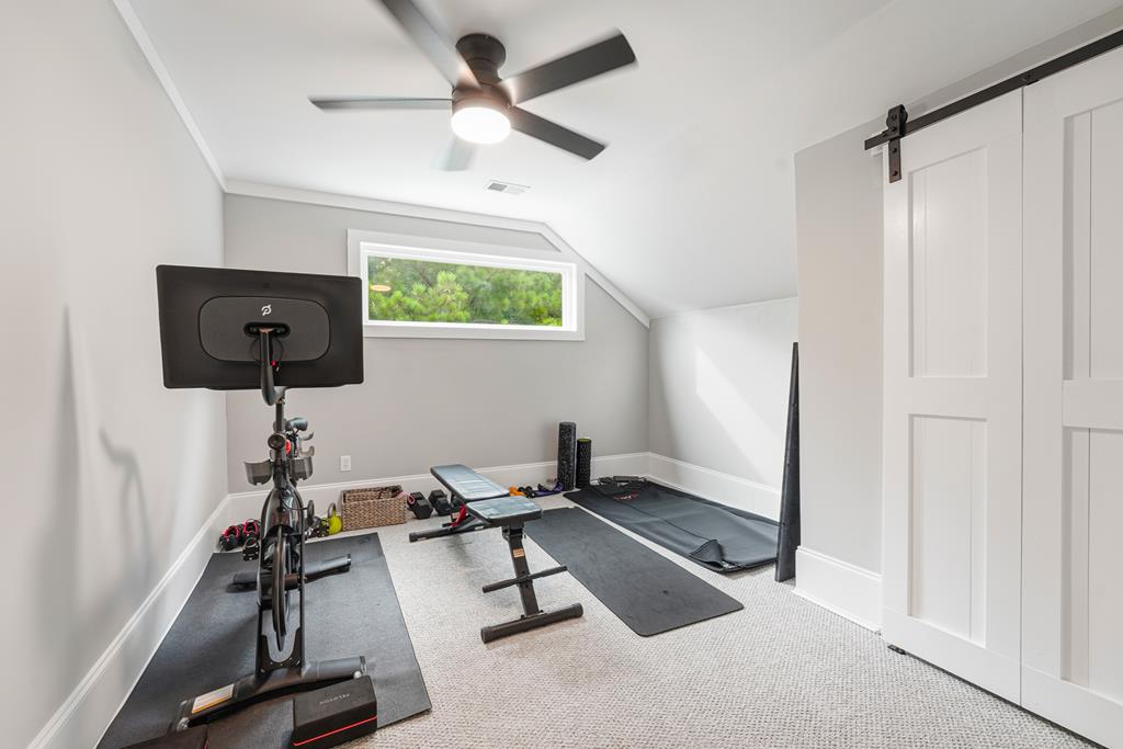 Home gym with a stationary bike, weight bench, and exercise mats beneath a sloped ceiling.