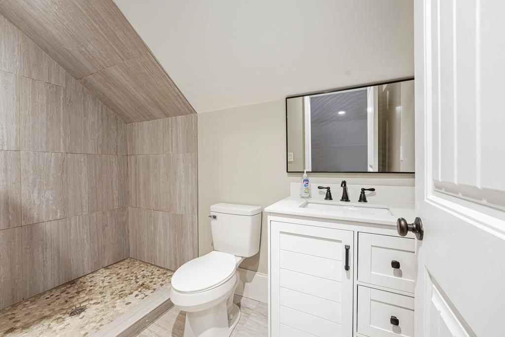 Bathroom with a tiled walk-in shower, pebble mosaic floor, and white vanity.
