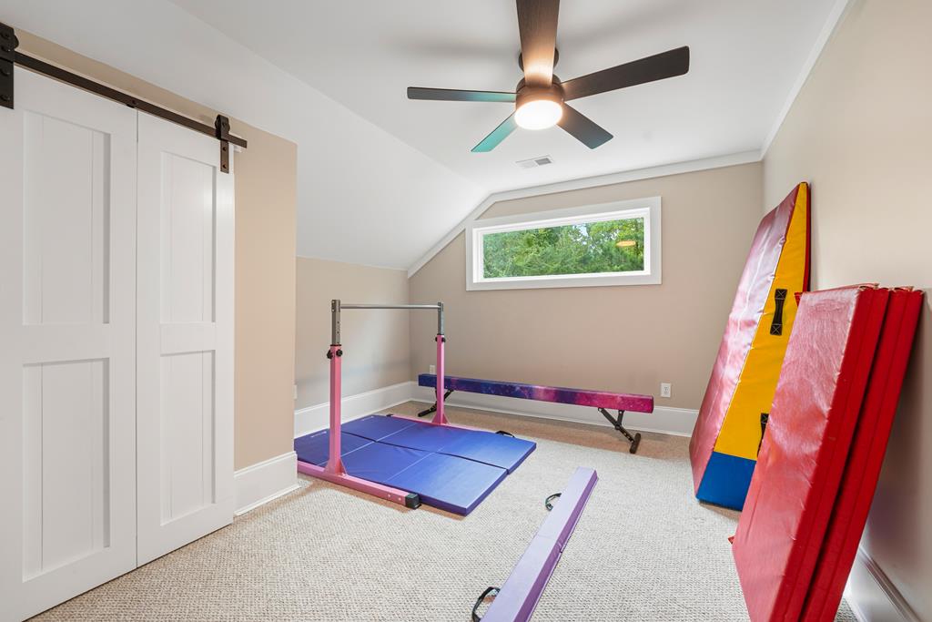 Exercise room with gymnastics mats, a balance beam, and a high window overlooking trees.