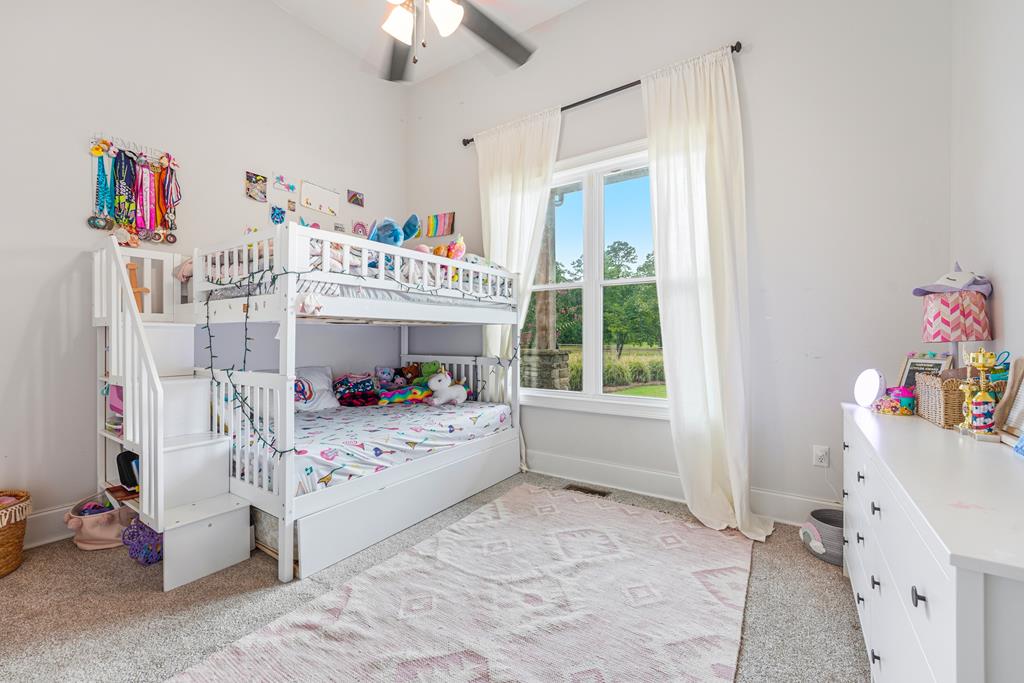 Children's bedroom with white bunk beds, colorful toys, and a large curtained window.