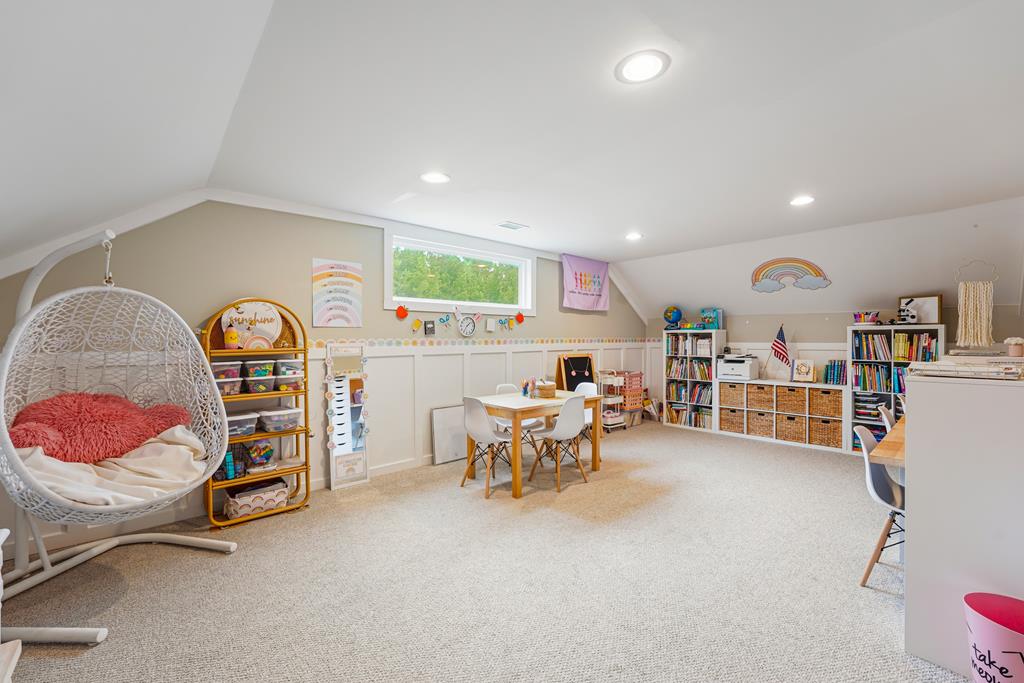Children's playroom with a hanging chair, activity tables, bookshelves, and organized storage.