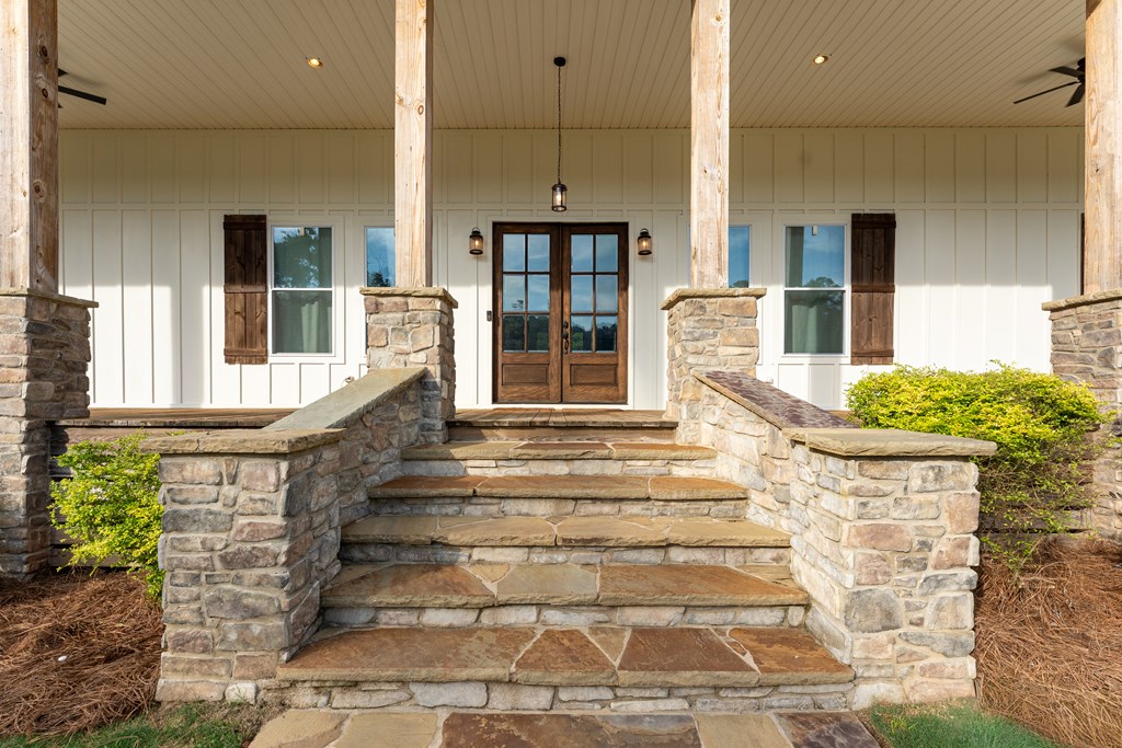 Home entrance with broad stone steps, stone railings, and dark wood-and-glass double doors.