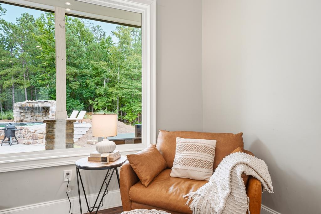 Leather armchair beside a large window overlooking a pool and wooded yard.