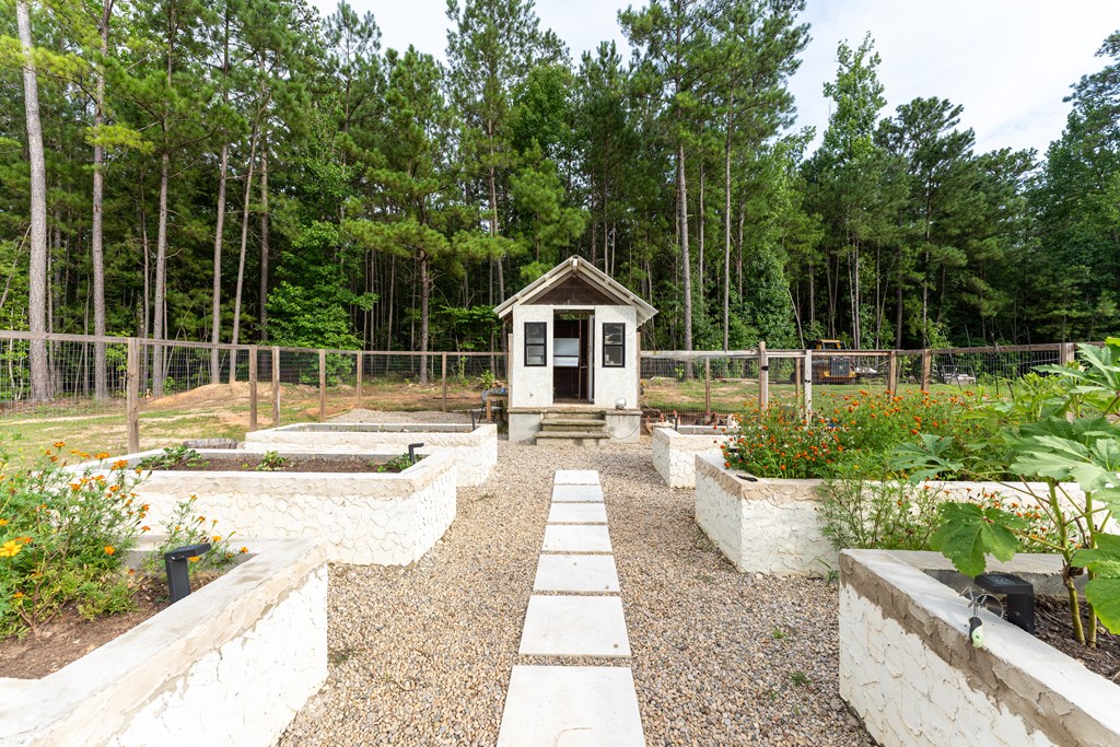 Landscaped garden with raised stone beds, a stepping-stone path, and a small white shed.