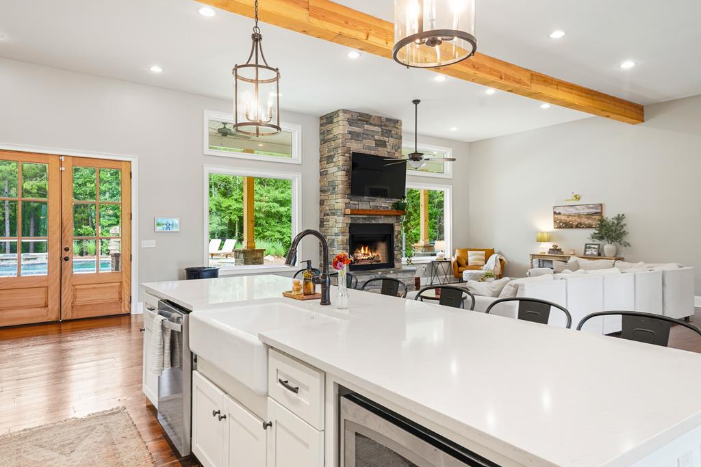 Open-plan kitchen and living room with a large white island and stone fireplace.