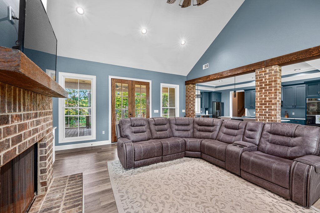 Living room with a gray sectional, brick fireplace, and glass doors opening to a deck.