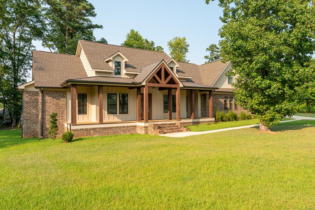 Home with a timber-framed entry, brick exterior, and broad green lawn.