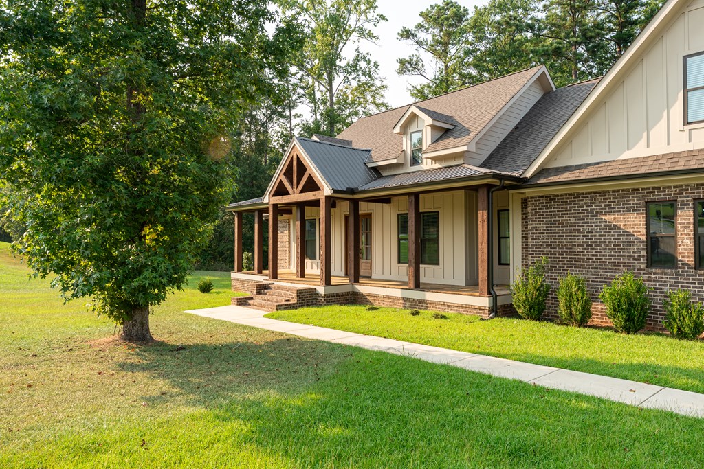 Home with a covered timber porch, cream siding, brick accents, and a walkway across the lawn.