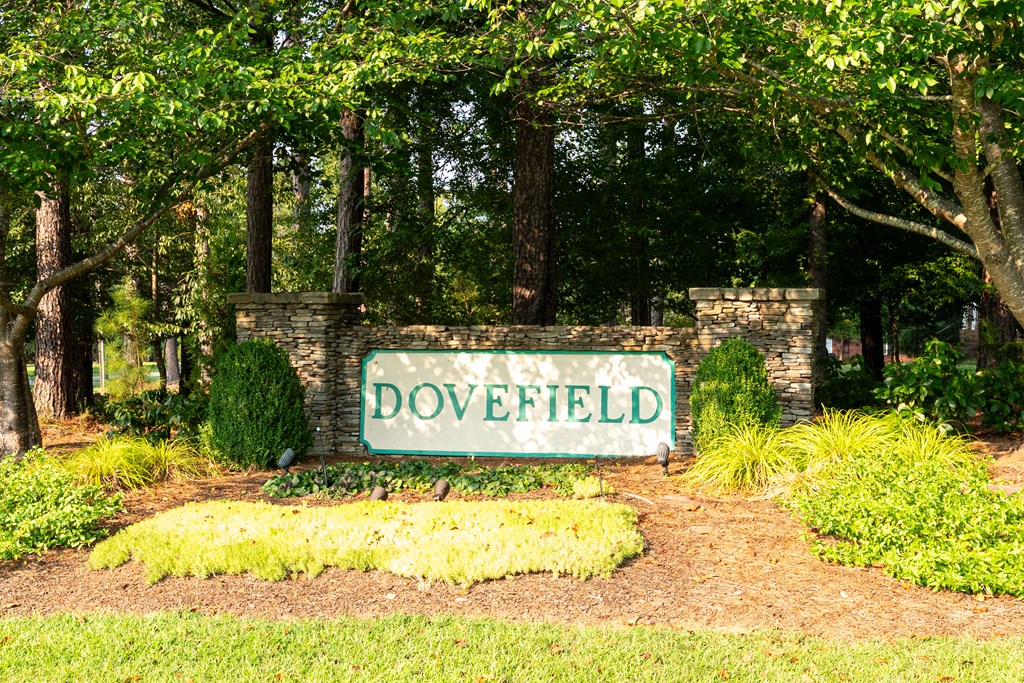 Dovefield community entrance sign set in a landscaped, wooded stone gateway.