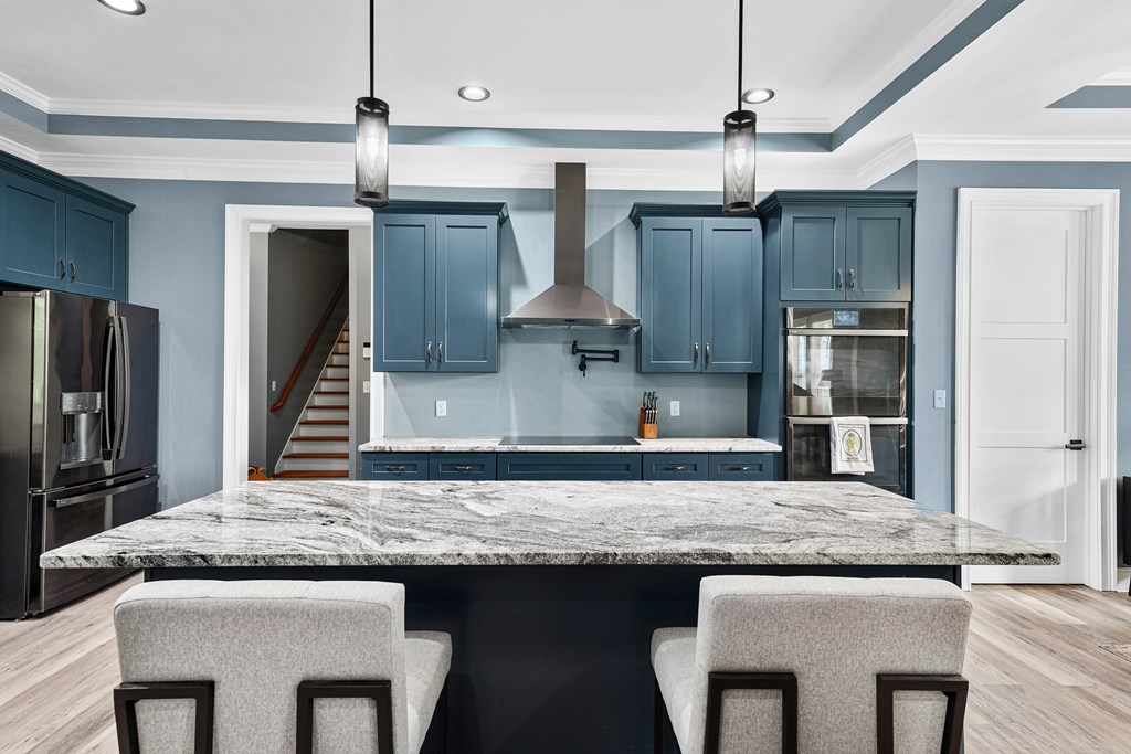 Modern kitchen with blue cabinets, a large stone island, and stainless steel appliances.