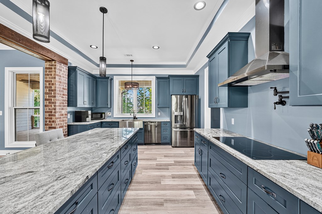 Modern kitchen with blue cabinets, stone countertops, a large island, and stainless steel appliances.