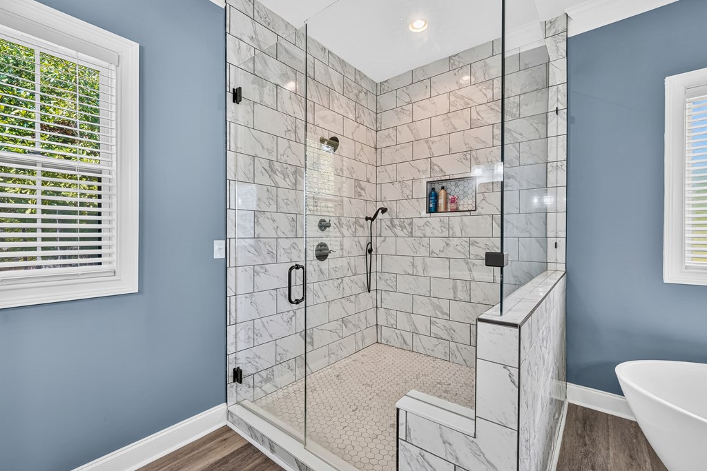 Bathroom with a spacious glass-enclosed shower, marble-look tile, and built-in bench.