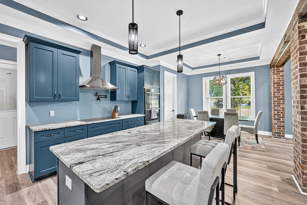 Kitchen with blue cabinetry, a large stone island, and an adjoining dining area.