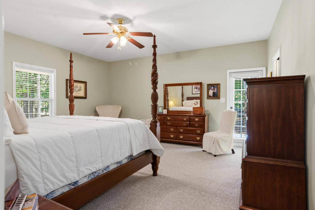 Bedroom with a dark wood four-poster bed, matching dresser, and windows with blinds.