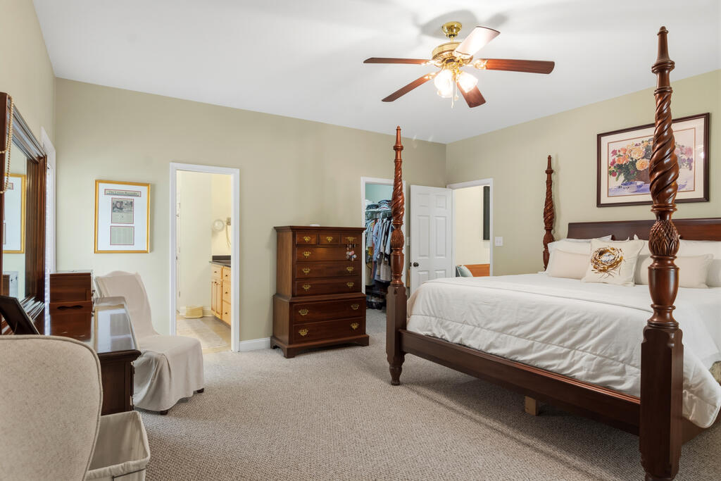 Bedroom with a dark wood four-poster bed, white bedding, and ceiling fan.