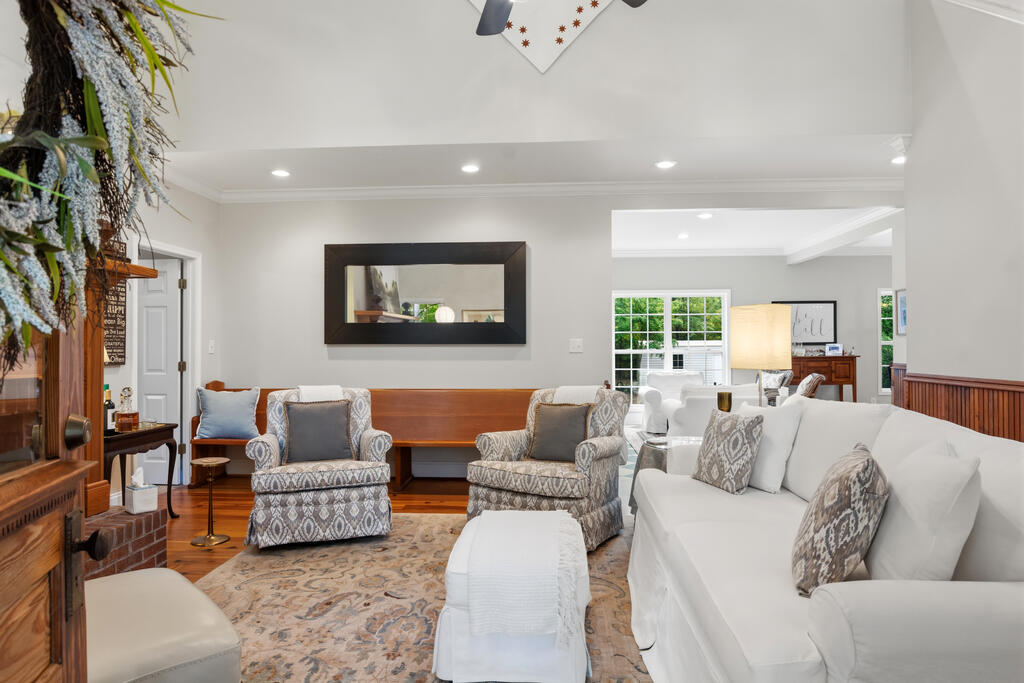 Living room with a white sofa, patterned armchairs, and a brick fireplace.