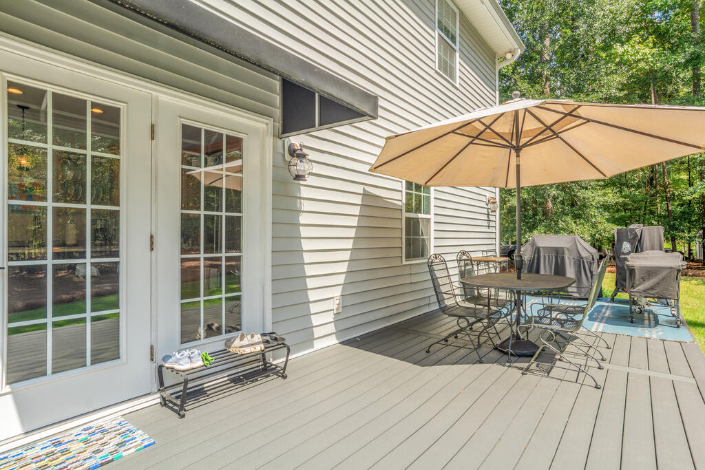 Back deck with a tan umbrella shading a metal patio dining set.