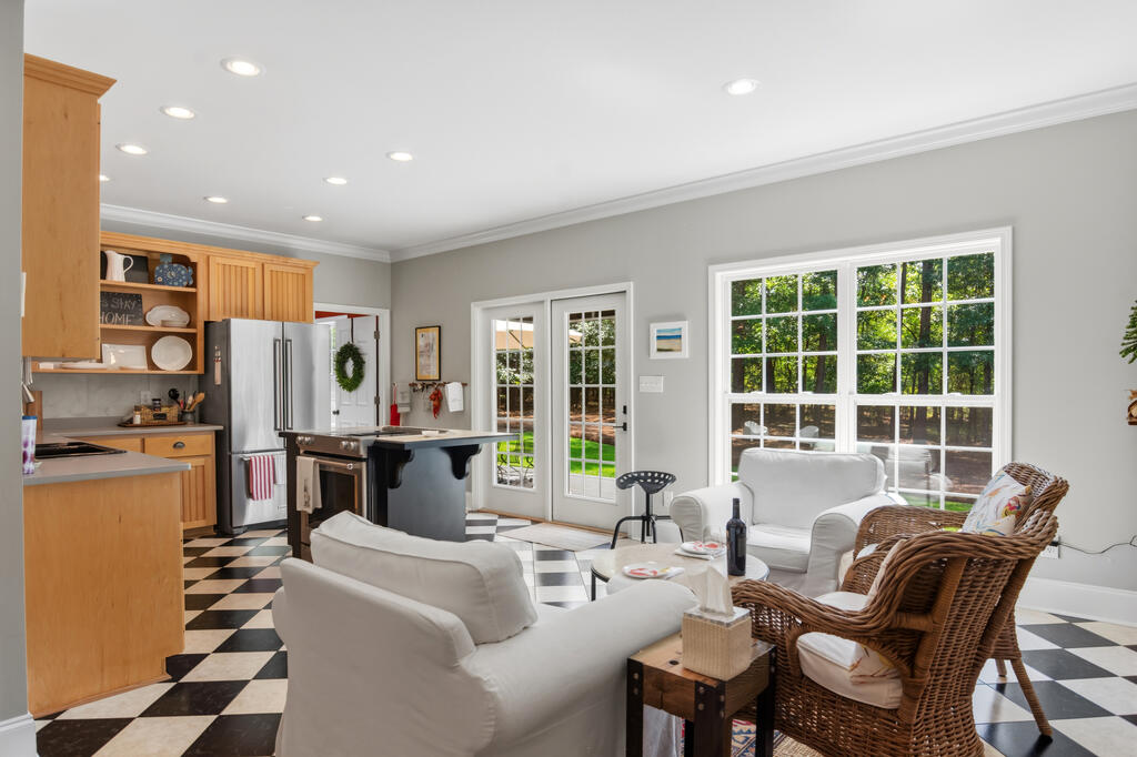 Open kitchen and sitting area with checkerboard floors, white seating, and garden-facing windows.
