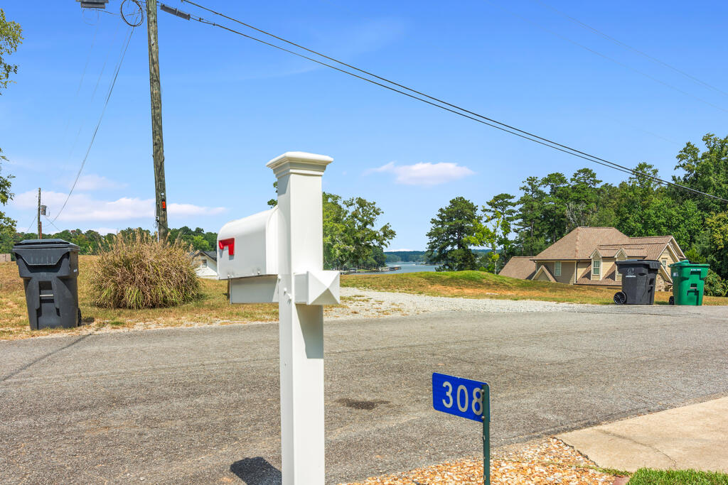 White mailbox and 308 address marker beside the road, with the lake visible in the distance.