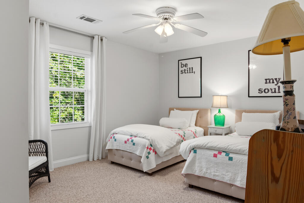 Bedroom with two twin beds, colorful quilt accents, and framed inspirational wall art.