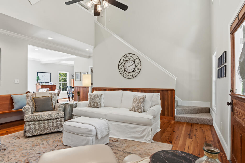 Living room with a vaulted ceiling, white sofa, hardwood floors, and carpeted stairs.