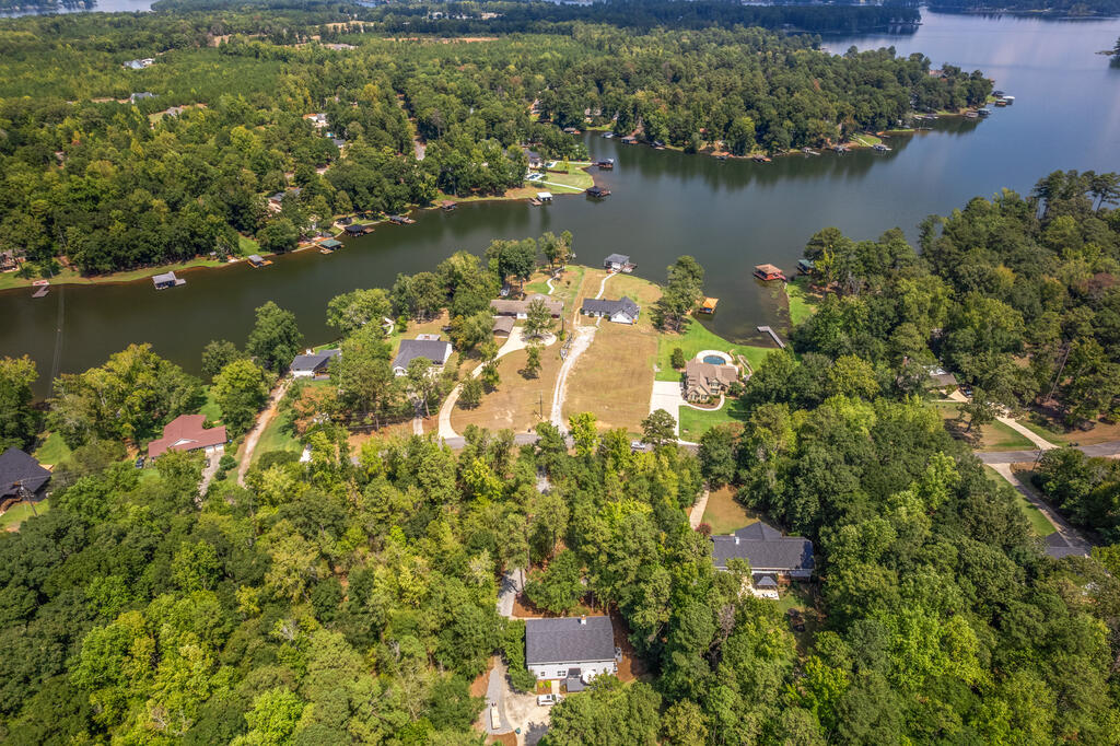 Aerial view of lakeside homes and docks along a wooded shoreline.