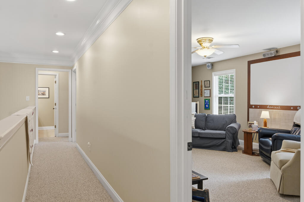 Carpeted hallway opening into a sitting room with gray sofas and a wall-mounted basketball hoop.