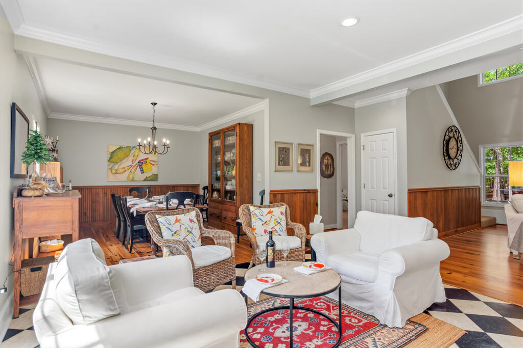 Living room with white sofas, wicker chairs, and an adjoining dining area.